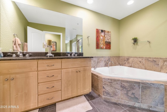 bathroom with a relaxing tiled tub, vanity, and tile patterned floors