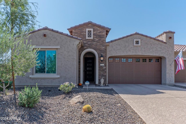 mediterranean / spanish-style house featuring concrete driveway, stucco siding, a tiled roof, and a garage