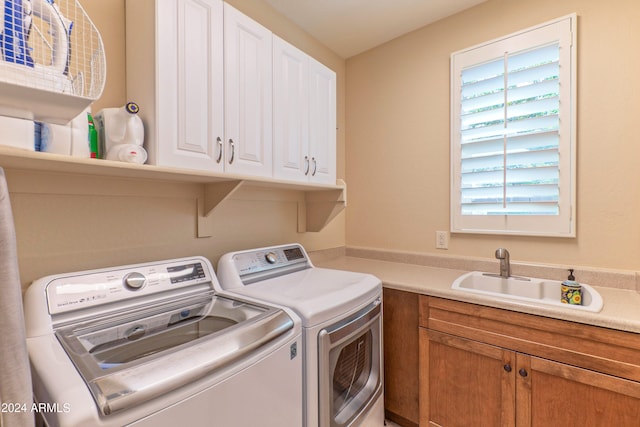 laundry area featuring washer and clothes dryer, a sink, and cabinet space