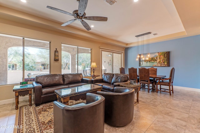 living area with ceiling fan with notable chandelier, baseboards, recessed lighting, and a raised ceiling