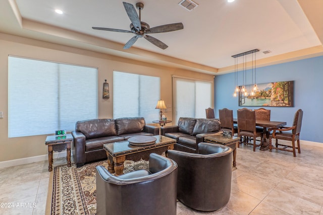 living area featuring a tray ceiling, visible vents, baseboards, recessed lighting, and a ceiling fan