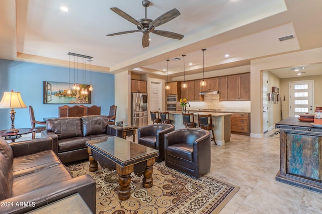 living area with ceiling fan with notable chandelier, light tile patterned flooring, a tray ceiling, visible vents, and recessed lighting