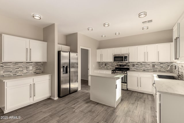 kitchen featuring stainless steel appliances, sink, a kitchen island, and white cabinets