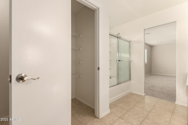 bathroom featuring tile patterned flooring and shower / bath combination with glass door