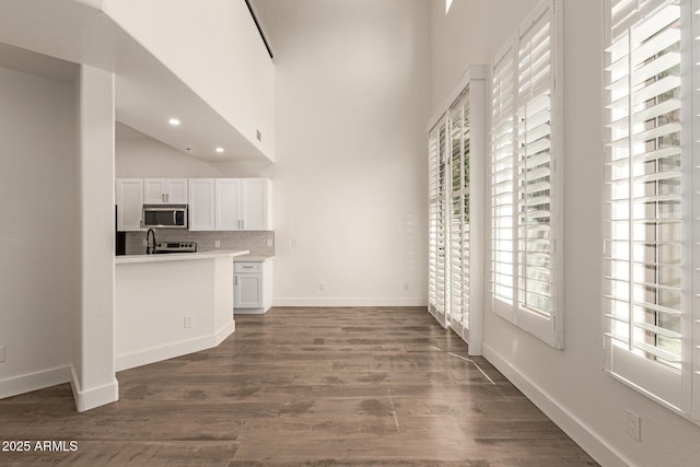 2019 E Campbell Ave Unit 110, Phoenix, AZ 85016 - kitchen featuring stainless steel microwave, white cabinetry, light countertops, dark wood-style flooring, and backsplash