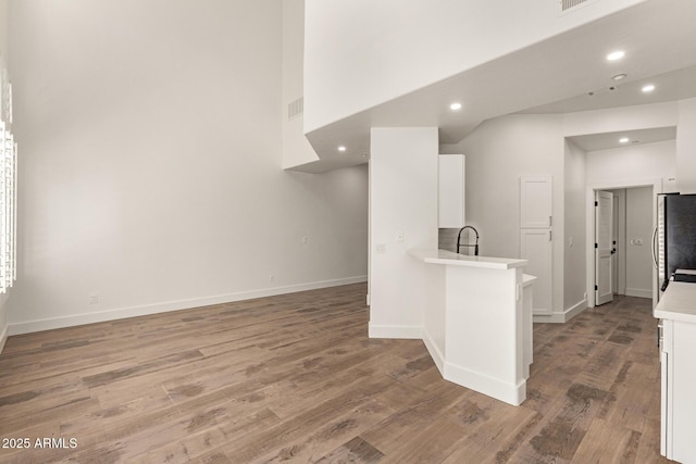 2019 E Campbell Ave Unit 110, Phoenix, AZ 85016 - kitchen featuring white cabinets, freestanding refrigerator, light countertops, light wood-style floors, and recessed lighting
