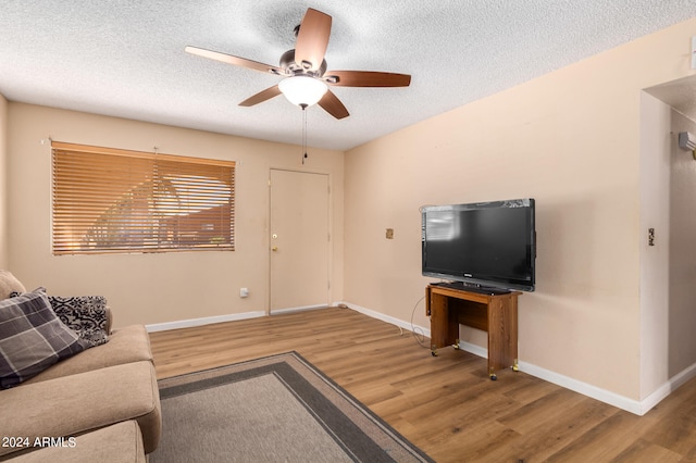 living room featuring ceiling fan, hardwood / wood-style flooring, and a textured ceiling