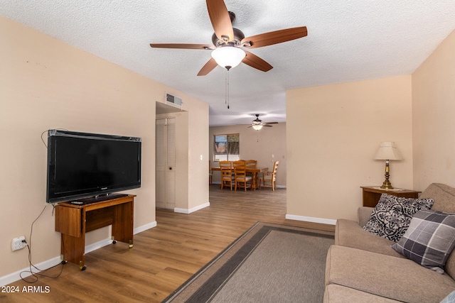 living room featuring ceiling fan, a textured ceiling, and hardwood / wood-style floors