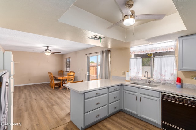 kitchen featuring black dishwasher, light hardwood / wood-style floors, sink, kitchen peninsula, and ceiling fan