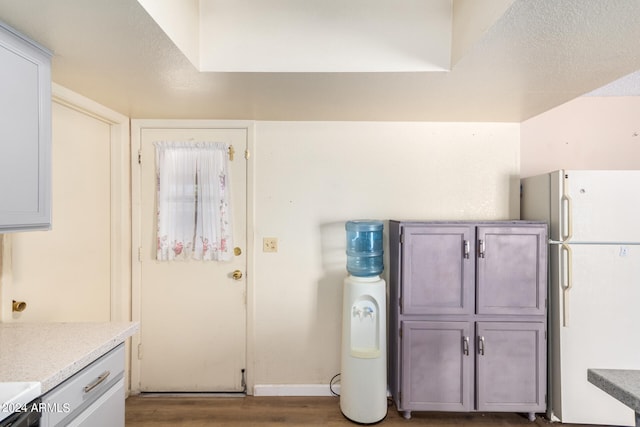 kitchen featuring gray cabinetry, white refrigerator, hardwood / wood-style floors, and a textured ceiling