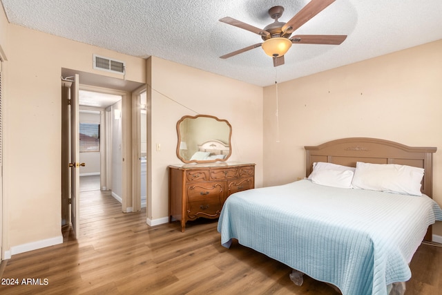 bedroom featuring ceiling fan, hardwood / wood-style flooring, and a textured ceiling