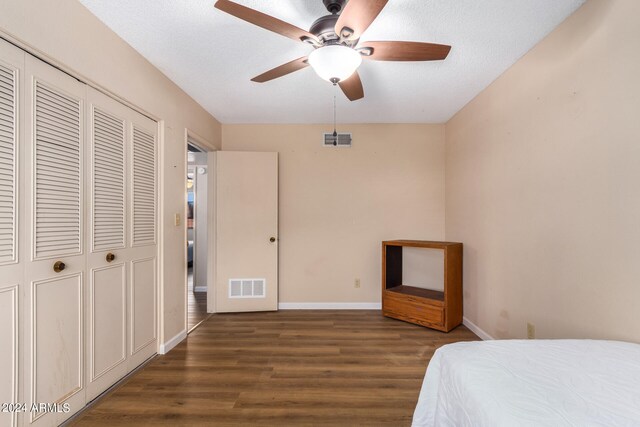 bedroom with a closet, ceiling fan, a textured ceiling, and dark hardwood / wood-style flooring