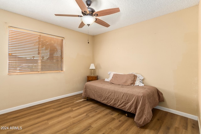 bedroom featuring ceiling fan, hardwood / wood-style floors, and a textured ceiling