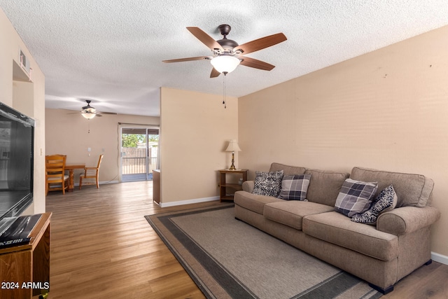 living room with ceiling fan, hardwood / wood-style floors, and a textured ceiling