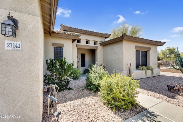 exterior space featuring a tile roof, fence, and stucco siding