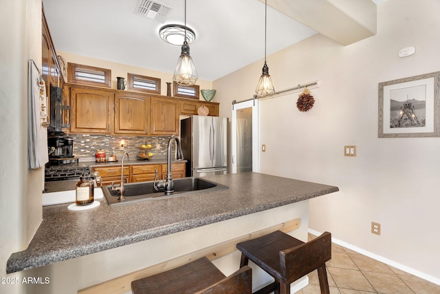 kitchen featuring dark countertops, visible vents, a barn door, freestanding refrigerator, and a sink