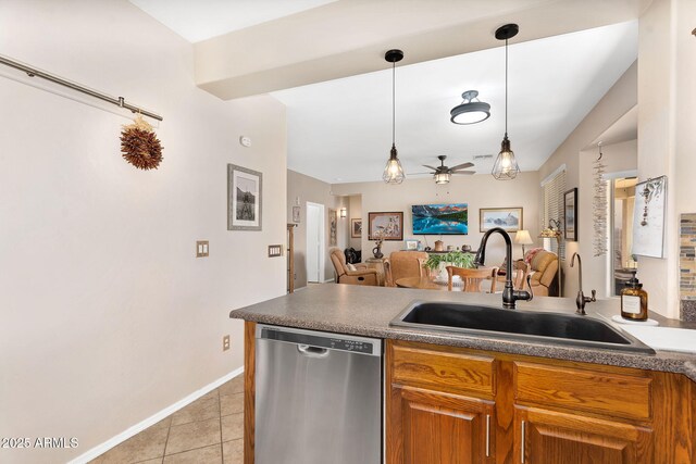 kitchen featuring open floor plan, dishwasher, light tile patterned floors, brown cabinetry, and a sink