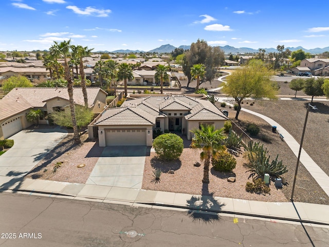 view of front of home featuring a residential view, a tile roof, driveway, a garage, and a mountain view