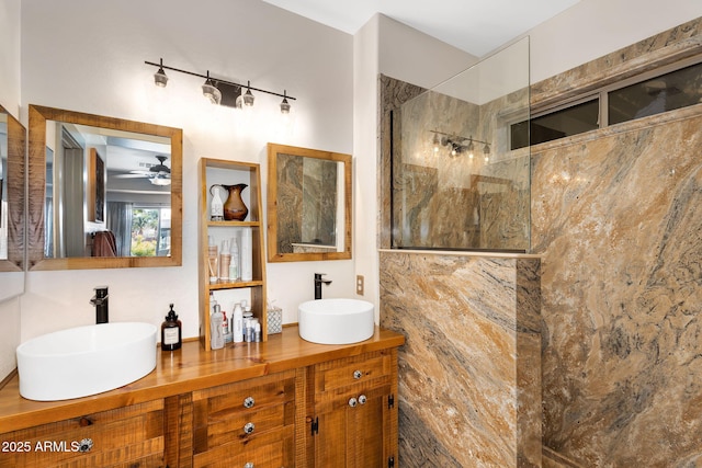 bathroom featuring a sink, a marble finish shower, and double vanity