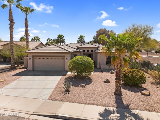 view of front of property with a tile roof, stucco siding, driveway, and an attached garage