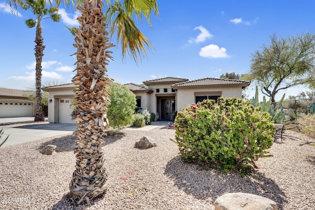 view of front of home featuring stucco siding, driveway, a garage, and fence