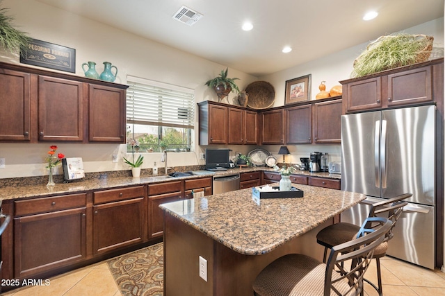 kitchen featuring stone countertops, appliances with stainless steel finishes, a kitchen breakfast bar, and a sink