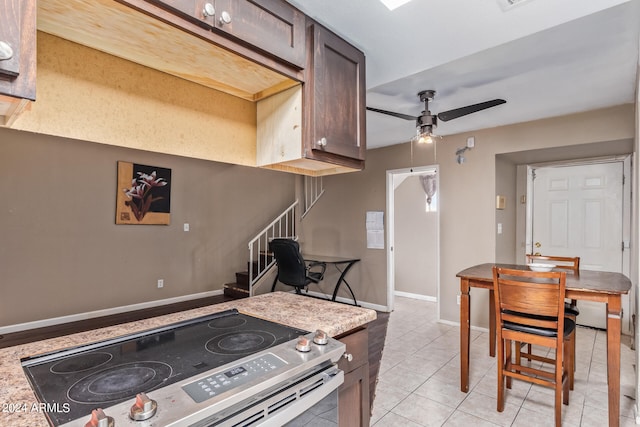 kitchen featuring stainless steel electric range oven, dark brown cabinetry, ceiling fan, and light tile patterned flooring