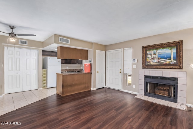 kitchen featuring ceiling fan, a fireplace, hardwood / wood-style floors, and white fridge