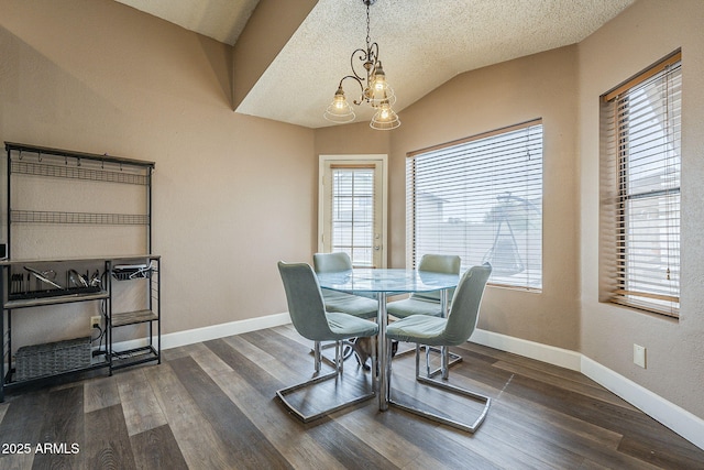 dining area with a chandelier, vaulted ceiling, dark wood finished floors, and baseboards