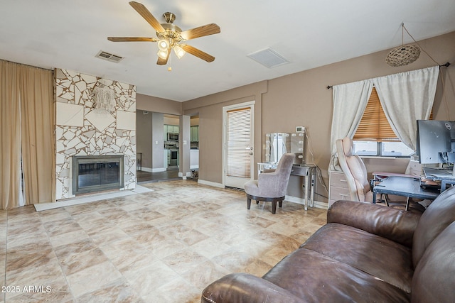 living area featuring baseboards, a premium fireplace, visible vents, and a ceiling fan