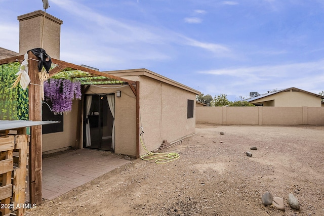 view of side of home with fence and stucco siding