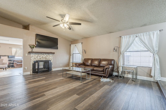 living room with ceiling fan, a fireplace, baseboards, vaulted ceiling, and dark wood finished floors