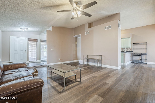 living area with lofted ceiling, baseboards, visible vents, and wood finished floors