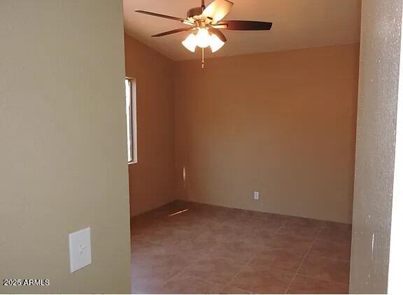 tiled spare room featuring ceiling fan