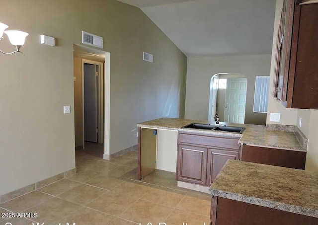 kitchen featuring vaulted ceiling, sink, and light tile patterned floors