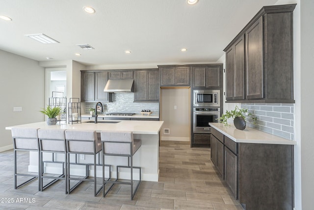 kitchen featuring appliances with stainless steel finishes, light wood-type flooring, a kitchen island with sink, and sink