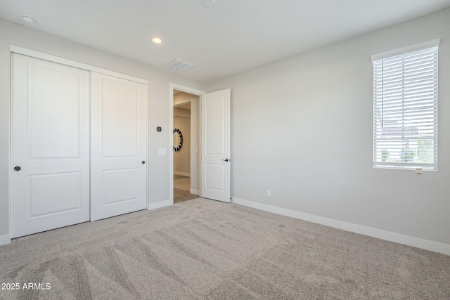 unfurnished bedroom featuring a closet and light colored carpet