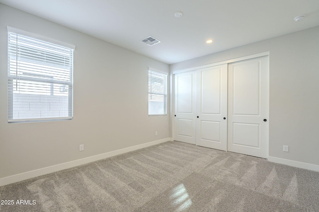 unfurnished bedroom featuring light colored carpet and a closet