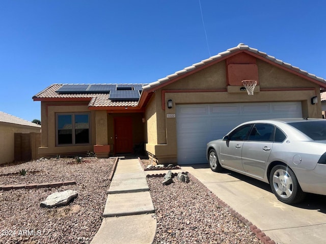 ranch-style house with a garage and solar panels