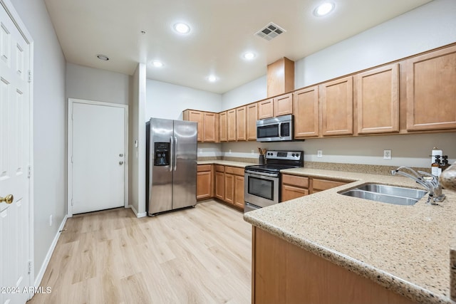 kitchen with light stone countertops, stainless steel appliances, light hardwood / wood-style flooring, and sink