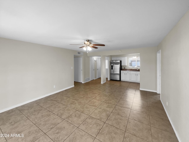 unfurnished living room featuring ceiling fan, sink, and light tile patterned floors