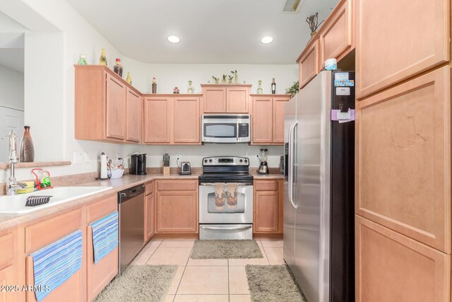kitchen with light brown cabinetry, visible vents, stainless steel appliances, and light tile patterned flooring