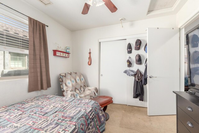 bedroom with a closet, light carpet, visible vents, and ceiling fan