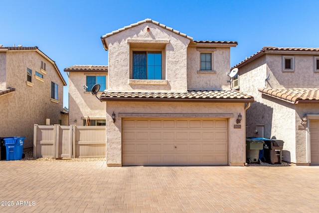 mediterranean / spanish-style home featuring a tile roof, decorative driveway, a garage, and stucco siding