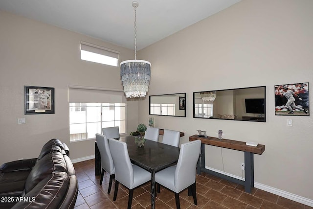 dining room with baseboards, a high ceiling, an inviting chandelier, and dark tile patterned flooring