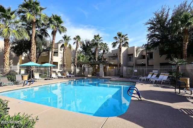 pool with a patio, fence, and a residential view