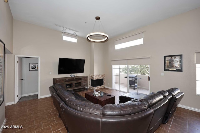 living room featuring track lighting, dark tile patterned floors, baseboards, and a towering ceiling