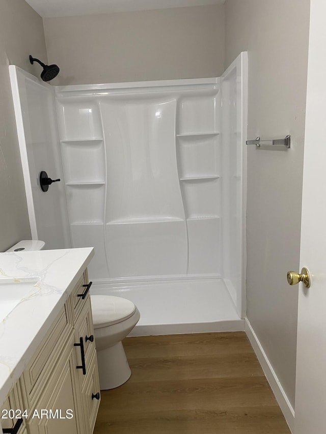 bathroom with a shower, hardwood / wood-style floors, vanity, and toilet