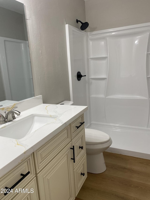 bathroom with hardwood / wood-style flooring, toilet, a shower, and vanity