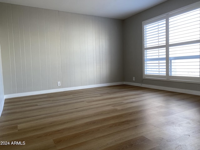 unfurnished room with wood walls and dark wood-type flooring